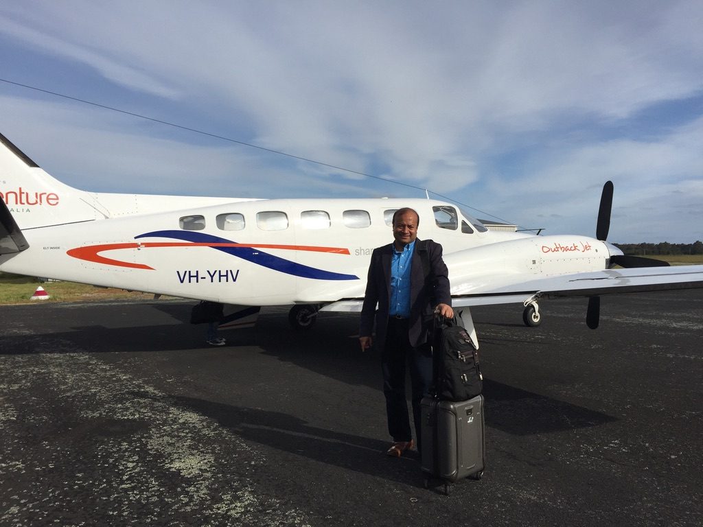 Sohail Hasnie with luggage beside a charter aircraft on a regional airstrip